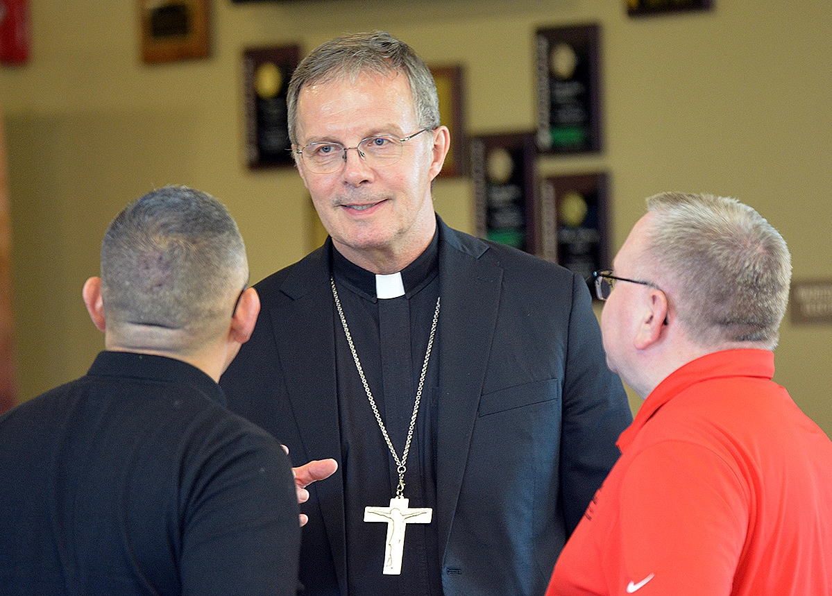 Bishop William Joensen talks to two people